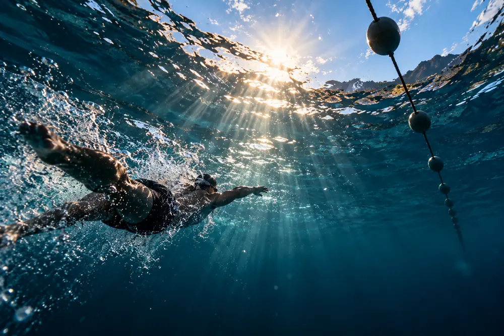 A swimmer underwater with sun rays